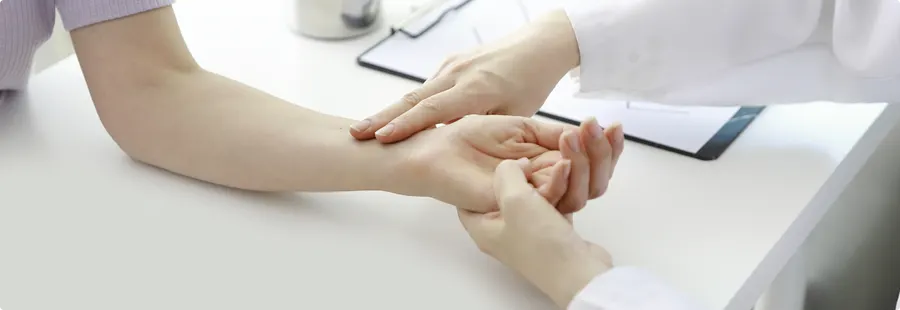 책상에 올린 손목에서 맥을 짚는 진찰 장면