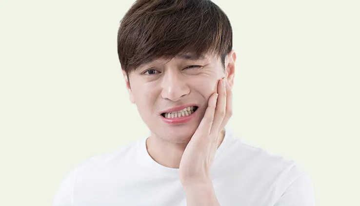 한쪽 볼을 손으로 감싸 쥐고 찡그린 모습